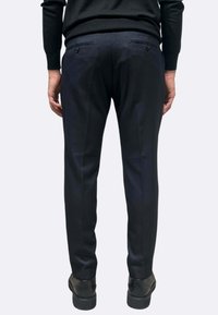 Pantaloni navy con vestibilità sartoriale, caratterizzati da una trama liscia, due tasche posteriori con chiusura a bottone e un design a gamba dritta.