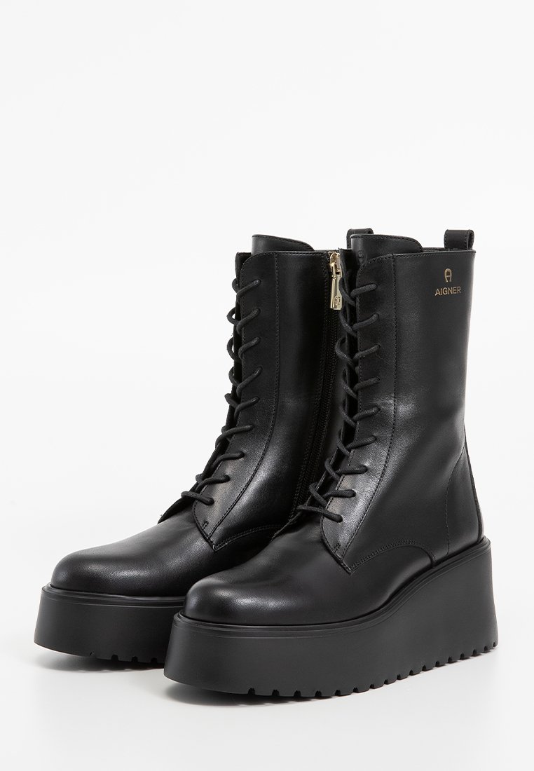 Schwarze Leder-Plateau-Stiefel mit vorderer Schnürung, seitlichem Reißverschluss, strukturierten Sohlen und goldenem Aigner-Logo an der äußeren Oberseite.