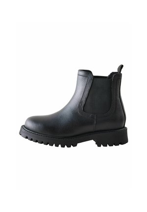 Botín Chelsea de cuero negro con paneles laterales elásticos, puntera redonda y suela de goma resistente. Cuenta con un tirador para facilitar el uso.