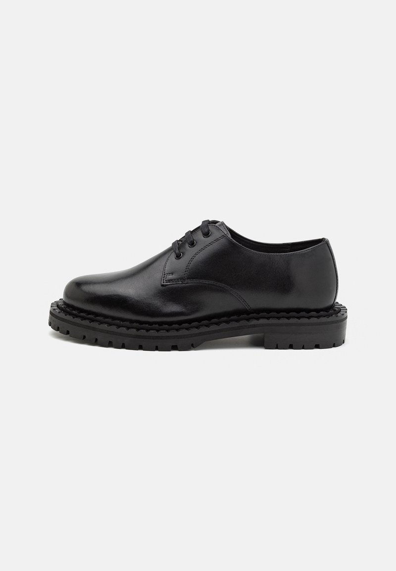 Chaussure noire en cuir à lacets avec semelle épaisse crantée, dessus lisse et bout arrondi, présentée de profil sur fond blanc.