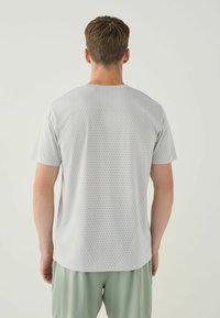 Light gray athletic t-shirt with a textured pattern, short sleeves, and a round neckline, paired with light green shorts.