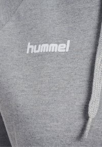 Sweatshirt gris à texture douce, avec un logo blanc "hummel" sur la poitrine et une capuche à cordon.