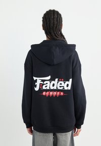 Svart hoodie med stor, vit text som läser "Fadëd" och "ECHÓES" med röda accenter. Mjuk material, lös passform, med huva och känguruficka.