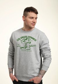 Grå sweatshirt med grøn grafik i vintage-stil af en baseballspiller. Ribbet manchetter og kant med rund halsudskæring.