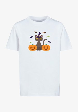 Hvid t-shirt med en grå kat med gule øjne og en lilla heksehue, flankeret af orange græskar og omgivet af små flagermus.