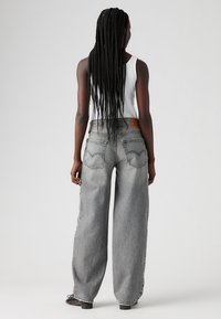 Wide-leg gray jeans made of denim, featuring a high waist, visible back pockets, and a leather tag on the waistband.