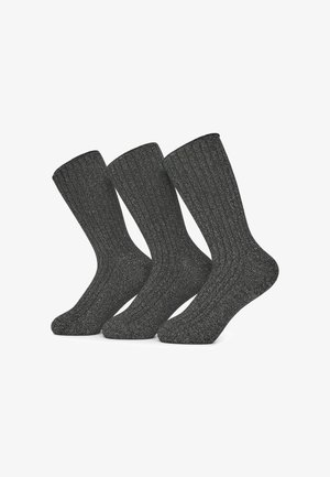 Tre paia di calzini a coste grigio scuro fino al polpaccio con fili d'argento esposti in posizione verticale su uno sfondo bianco.