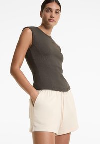 Donkergrijze geribbelde tanktop met een aansluitende pasvorm, gecombineerd met lichtbeige short met koord, voorzien van zijzakken en een zachte stoftextuur.