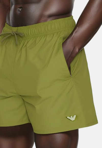 Shorts de bain verts en tissu léger, dotés d'une taille élastique avec cordon de serrage, de poches latérales et d'un emblème sur l'ourlet.