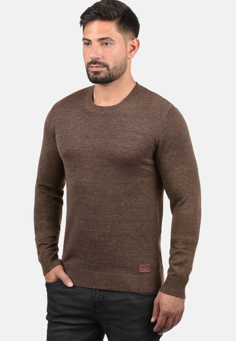 Brun crewneck genser med lange ermer, ribbede mansjetter og fald, myk tekstur og en liten merkelapp nederst til venstre.
