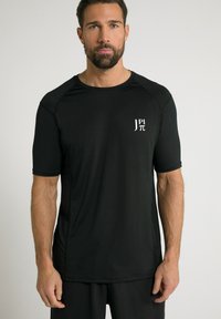 Sort atletik skjorte lavet af et glat, åndbart stof. Har korte ærmer, rund hals og et lille hvidt logo på brystet.