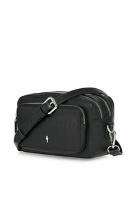 Czarna skórzana torba na ramię z podwójnymi zamkami, regulowanym paskiem oraz małym srebrnym emblematem ptaszka na przedniej kieszeni.