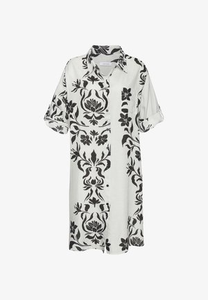 Baltas krekls-vārts ar melniem ziedu rakstiem, pogu priekšpuss un sarullētām piedurknēm. Izgatavots no viegla auduma ar brīvu piegriezumu.