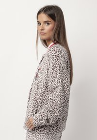 Giacca in pile con stampa leopardata, maniche lunghe, dettagli rosa e tasche frontali. Texture morbida con vestibilità rilassata e dettagli ricamati.