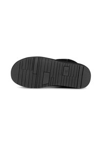 Suela de zapato de goma negra con una superficie texturizada y ranuras horizontales y verticales para mejor agarre. Presenta una puntera y un talón curvados.