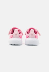 Sneaker rosa con tomaia in rete, morbide accentuazioni sul tallone e suola in gomma bianca. Presenta maniglie e elementi di design a contrasto.