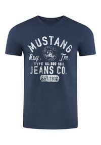 Marineblauwe katoenen t-shirt met korte mouwen heeft een verwassen witte opdruk met de tekst "MUSTANG JEANS CO." en een ronde embleem.