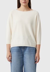 Jasnokremowy sweter z szerokim dekoltem typu łódka i rękawami 3/4, wykonany z miękkiego materiału. Ma luźny fason i podkreślone ściągaczami brzegi.