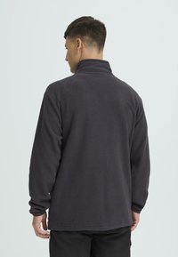 Tumehall hall kašmiirist üle pea tõmbatav pusa kõrge krae, pikad varrukad ja pehme tekstuuriga. Lihtne disain, ilma nähtavate mustrite või kaunistusteta.