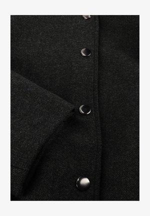 Zwarte herringbone wollen jas met een gestructureerde stof, grote zwarte knopen en een omgeslagen mouw met een nette afwerking.