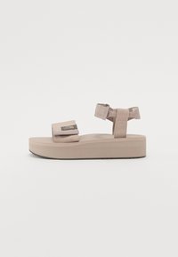 Beige plattform sandaler med stoffremmer, justerbare borrelåser, rillet såle, og teksturert fotseng.