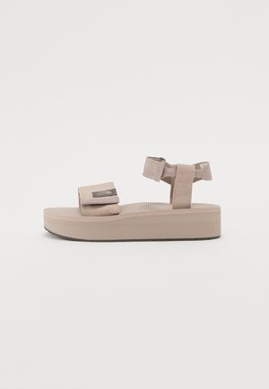 Beige platform sandals with fabric straps, adjustable hook-and-loop fasteners, ridged sole, and textured footbed.