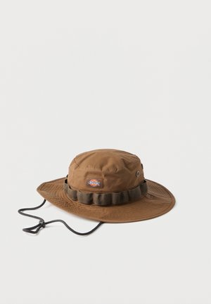 Brauner breitkrempiger Boonie-Hut mit einem Dickies-Logoaufnäher, verstellbarem Kinnriemen und einem Stoffband mit aufgenähten Schlaufen rund um die Krone.