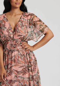 Abito maxi floreale in tessuto trasparente, con motivi di foglie rosa e marroni, scollatura a V e maniche voluminose con vita arricciata.