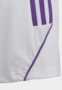 Witte sportshirt met paarse gestreepte accenten, een mesh zakdetail en contrasterende paarse bies langs de zoom.