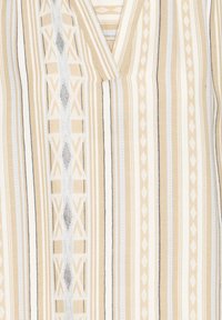 Tissu beige et crème avec des motifs à rayures verticales, des dessins géométriques et des textures subtiles agrémentées d'accents bleus et noirs.