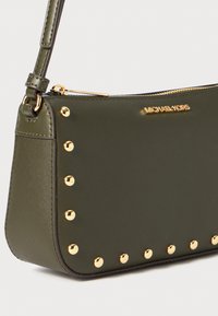 Olive green crossbody bag with structured shape, gold-tone hardware, and studded accents along one side. Zip closure at the top.