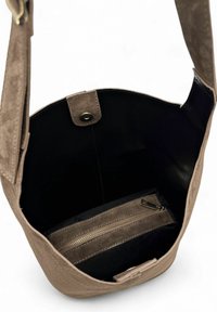 Sac fourre-tout en daim de couleur marron clair, avec un intérieur noir. Dispose d'une fermeture à pression magnétique et d'une poche intérieure zippée pour l'organisation.