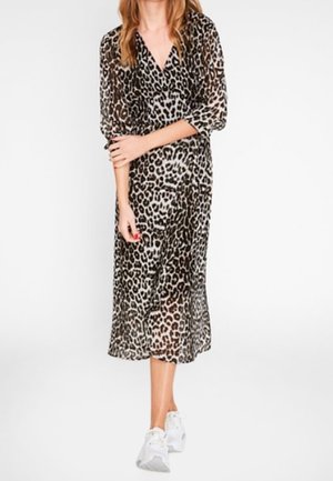 Robe en tissu transparent à imprimé léopard, manches longues et col en V. Modèle mi-long, porté avec des baskets blanches.