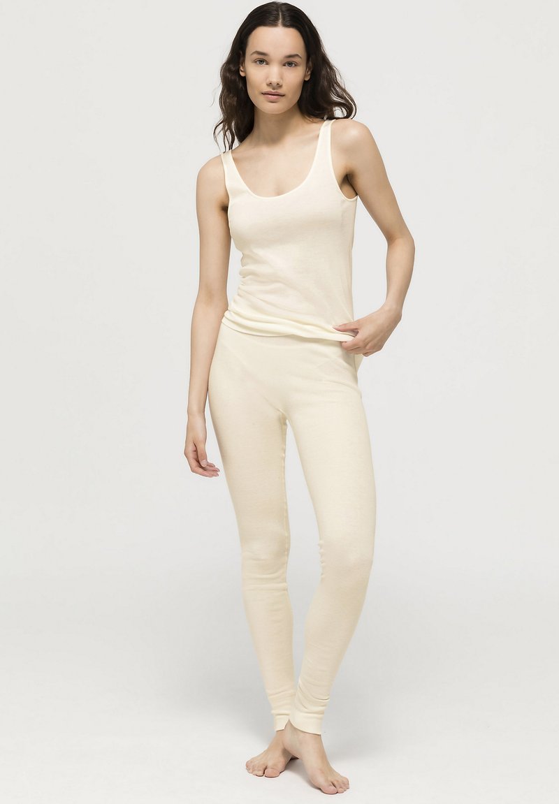 Krémový top na ramínka a legíny vyrobené z měkké látky; top má široká ramínka, legíny mají přiléhavý střih s žebrovanými lemy.
