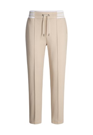 Beżowe spodnie dresowe ze ściągaczem w talii, ozdobione białym paskiem z elastanu. Posiadają boczne kieszenie i prosty krój nogawek.
