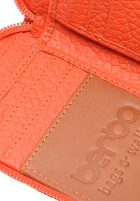 Oranje gestructureerde leren portemonnee interieur met ritssluiting; heeft een gladde bruine leren sectie met het merkembleem. 
