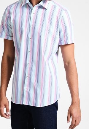 Man wearing a short-sleeve, buttoned shirt with vertical pastel stripes in blue, pink, and white paired with dark pants.