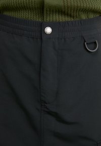 Černé šortky s elastickým pasem, vybavené kovovým knoflíkem a detailem úchytky. Hladký povrch, jednoduchý design a minimální švy.