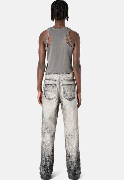 Gray ribbed tank top with cutout shoulders paired with faded gray and black wide-leg jeans featuring back pockets and a textured finish.