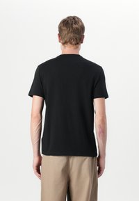 Black short-sleeve t-shirt made of cotton, featuring a crew neck, a straight cut, and a smooth texture. Back view shows minimal design.