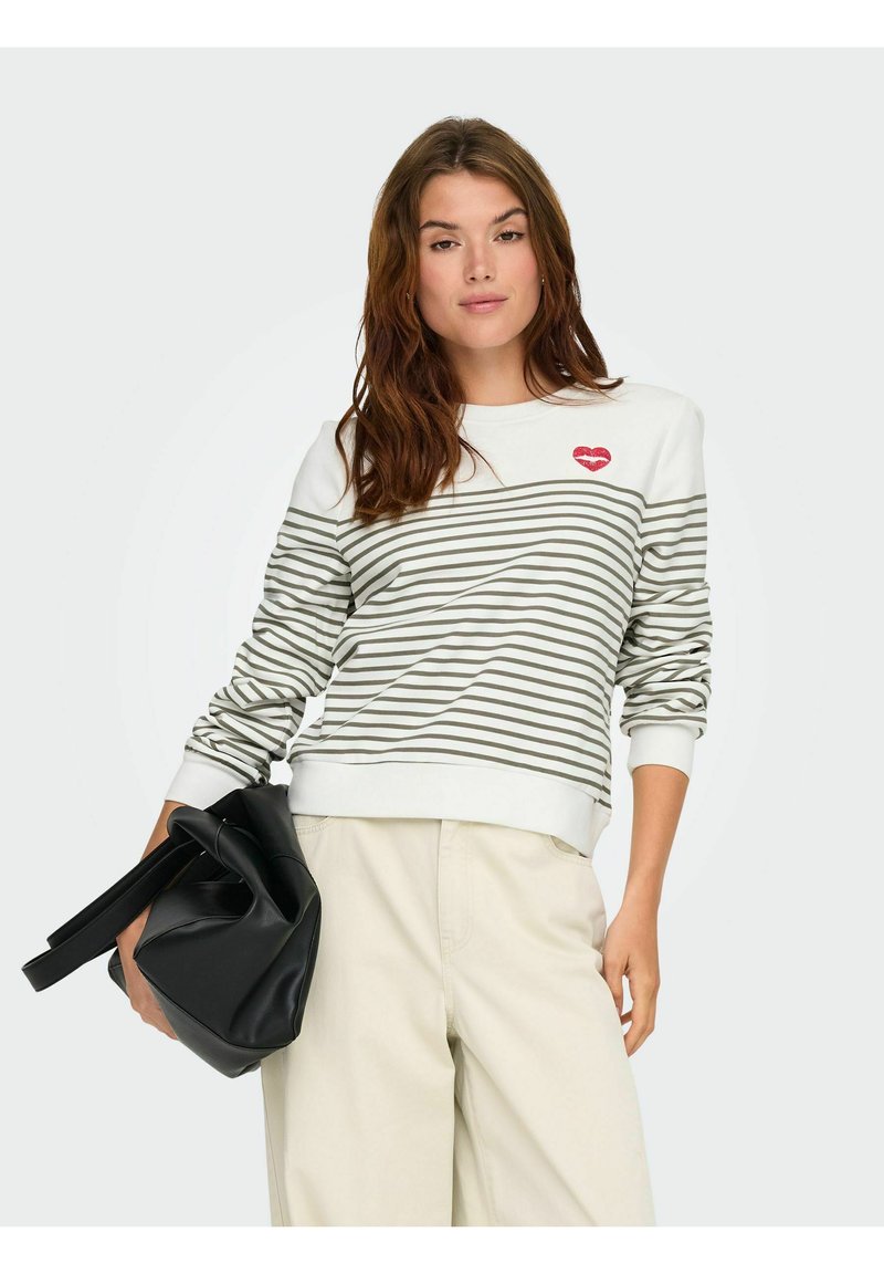 Sweter w paski w kolorze kremowym i oliwkowym z grafiką czerwonej szminki, okrągłym dekoltem, ściągaczami oraz luźnym krojem, w połączeniu z czarną torebką.