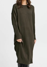 Vestito maglione in verde oliva scuro, con polsini e orlo a costine, vestibilità rilassata e spacco laterale per facilitare i movimenti.