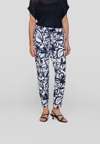 Navy floral-print drawstring pants with a white background, featuring soft fabric, slim fit, and elastic waist. Styled with black strappy sandals.