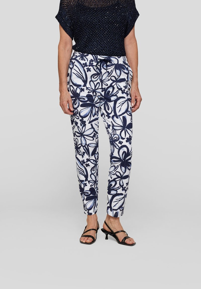 Navy floral-print drawstring pants with a white background, featuring soft fabric, slim fit, and elastic waist. Styled with black strappy sandals.