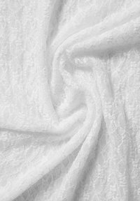 Tela de encaje blanca con un patrón floral, que presenta una textura transparente y un delicado detallado, drapeada y doblada para mostrar su naturaleza fluida.