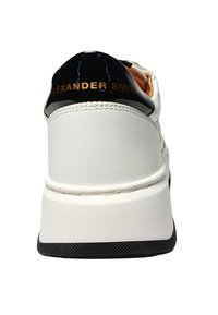 Witte leren sneaker met een glanzende zwarte hiel, gouden logo en een gestructureerde zwarte zool. Heeft een gladde textuur en een moderne silhouet.