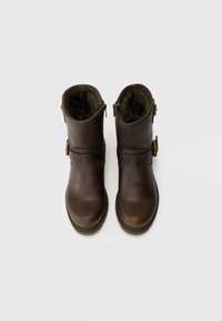 Botas de tornozelo de couro castanho com um interior forrado suave, duas correias ajustáveis e um design de bico arredondado. Sola texturizada para aderência.