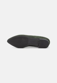 Scarpa piatta verde in suede con punta affusolata, dotata di una suola in gomma nera con motivi antiscivolo per una migliore aderenza. Design minimalista, senza hardware visibile.