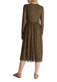 Långärmad klänning i grön med blommönster. Det lätta tyget har en figurnära överdel och en flödande kjol, med en knäppning i ryggen.