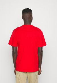 Rød bomulds t-shirt med korte ærmer, rund halsudskæring og en afslappet pasform. Glat tekstur uden synlige mønstre eller accenter.